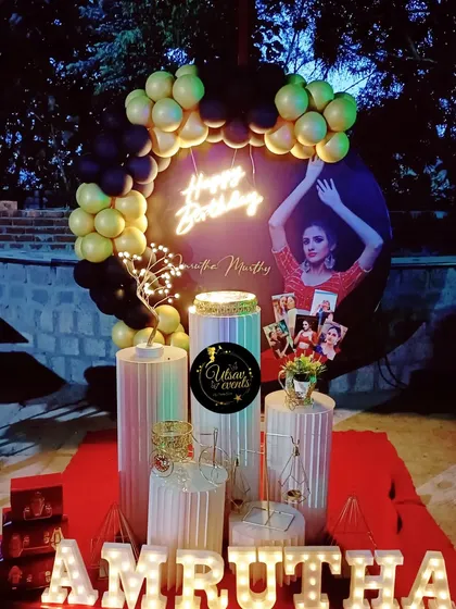 A personalized birthday setup with a custom photo backdrop. The balloon arch and plinth arrangement are designed to complement the photo.
