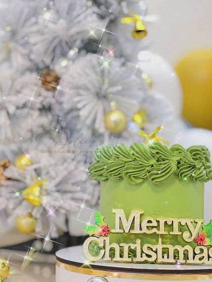 A simple and festive 'Merry Christmas' bento cake. The green frosting and gold topper against the sparkly Christmas tree background make it perfect for a holiday celebration.