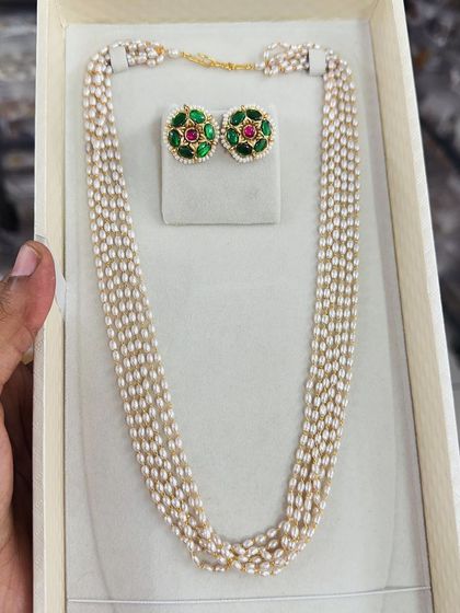 This elegant set pairs a multi-strand pearl necklace with beautiful stud earrings featuring green and red stones. It's a simple yet sophisticated choice for any occasion.