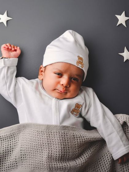 A sweet "twinkle, twinkle, little star" themed photo. The baby is dressed in a cozy white onesie and tucked under a blanket, set against a starry backdrop for a magical, sleepy-time feel.