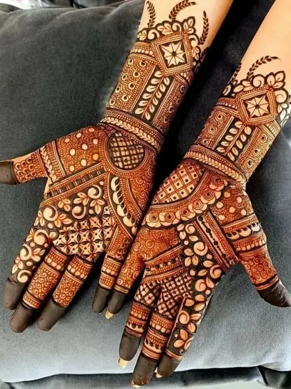 A contemporary take on traditional mehndi, this design uses geometric shapes and bold floral patterns. The dark fingertips provide a classic finishing touch.