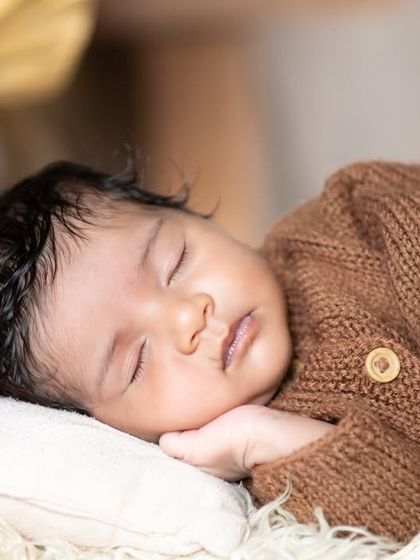 A close-up of a newborn sleeping on a tiny bed, looking perfectly peaceful.