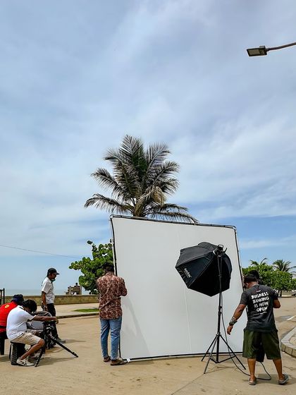 The crew setting up a large reflector for a beachside shot. This is essential for controlling the natural light and getting that perfect, soft illumination.