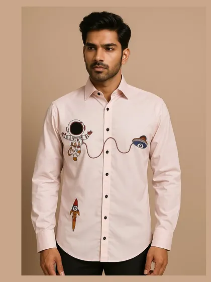 Showcasing a playful side, this light pink bespoke shirt is detailed with quirky, colorful hand embroidery of an astronaut and rocket. The design adds a touch of personality to a classic button-down, perfect for a smart casual look.