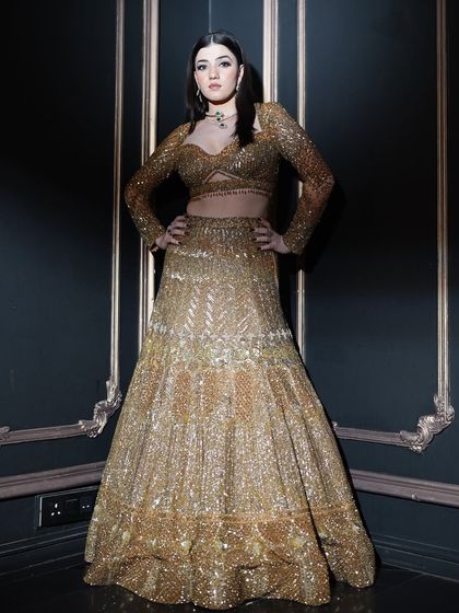 This powerful pose showcases the entire ensemble. The makeup was designed to be dramatic and confident, matching the energy of the heavily embellished golden outfit.