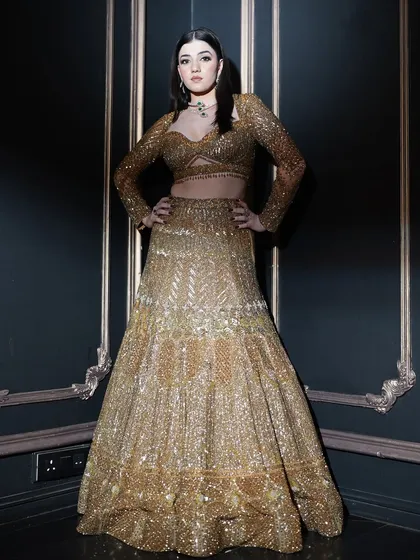 This powerful pose showcases the entire ensemble. The makeup was designed to be dramatic and confident, matching the energy of the heavily embellished golden outfit.