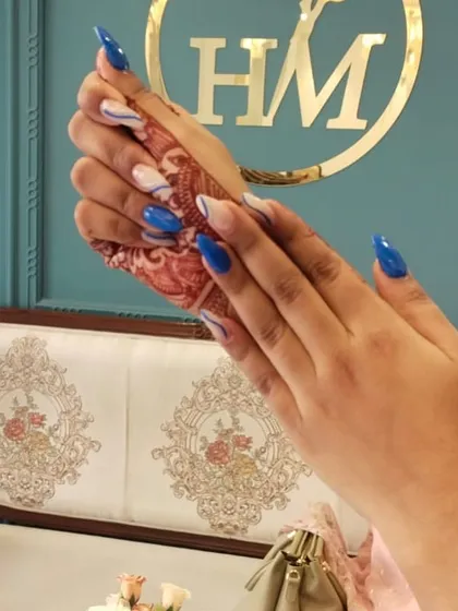 This is a great example of modern, graphic nail art. I combined a bold royal blue with a negative space background, using fine white and black lines to create a striking swirl pattern on these sharp stiletto nail extensions.