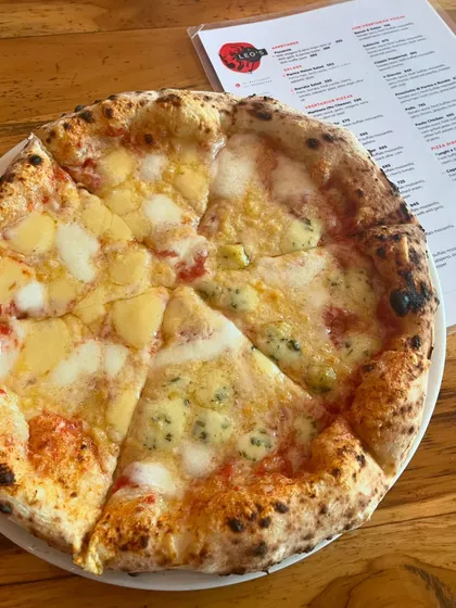 Our Quattro Formaggi pizza, sitting next to the menu. It's a tough choice with so many good options.