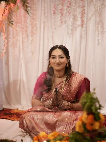 The bride joins her hands in prayer, her makeup looking soft and radiant.