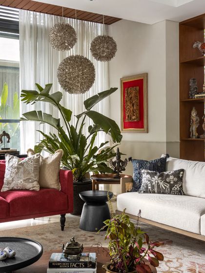 The living room was built around this bold red couch, which adds a vibrant pop of color and energy. It’s surrounded by the client's art, indoor plants, and a mix of textures to create a space that is full of life.