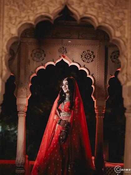 I use creative lighting to craft dramatic and artistic bridal portraits. This shot uses shadows and a single light source to highlight the bride's elegance and the richness of her red lehenga, turning a photo into a masterpiece.