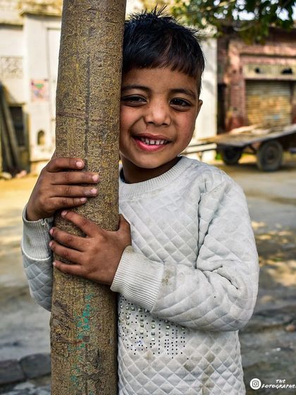 This is a wider shot of the smiling boy from Punjab. Including more of the background gives context to the scene, showing the rustic village environment where I took this candid portrait.