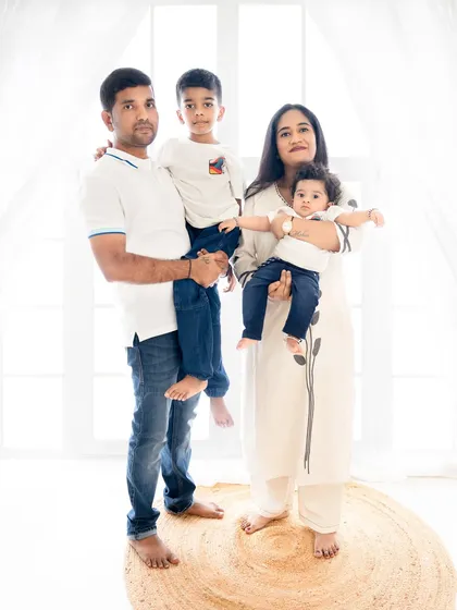 A lovely standing portrait of a family of four. The parents hold their children, creating a sense of unity and love in this beautifully lit studio photo.