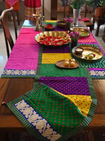 The full festive tablescape, with the patchwork Bandhani runner layered over the pink and purple raw silk tablecloth.