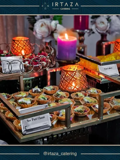 A beautiful tray of assorted appetizers, including Sev Puri Chaat and Bruschetta. The candlelight from the decorative votives adds a warm glow to this inviting spread.
