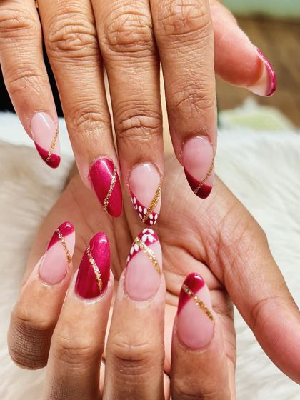 A chic and festive design with red cat eye polish, gold glitter lines, and delicate white floral details.