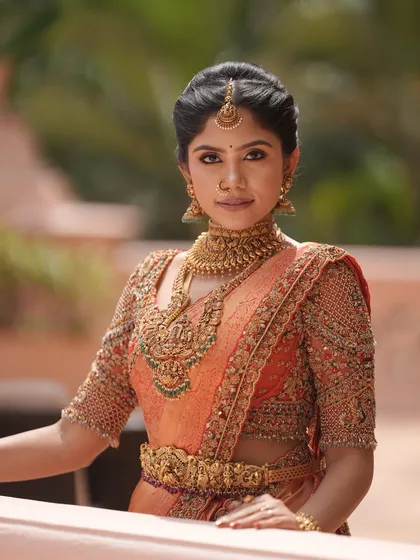 The quintessential South Indian bride, poised and elegant. I designed this rich orange silk saree and heavily embellished blouse to honor tradition while feeling completely personal and unique to her.