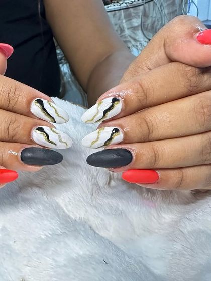 A bold, matte set with a mix of red, black, and white nails featuring a black and gold marble-like vein design.