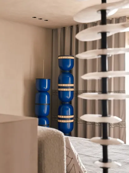 A detail shot focusing on the vibrant blue stacked vases, which serve as a striking art piece in the bedroom. This highlights our method of using bold accents to punctuate an otherwise neutral and calming space.
