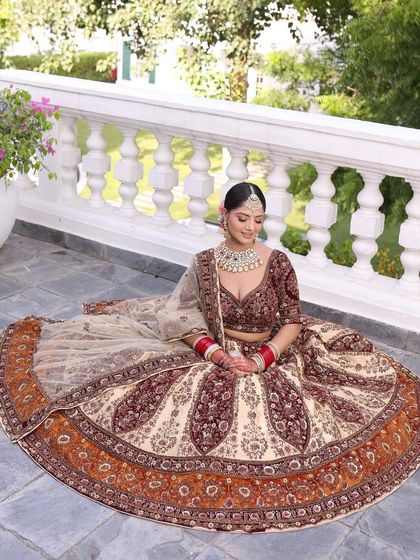 A full-length shot of the bride in the beige and maroon lehenga, showing how the outfit creates a beautiful silhouette.