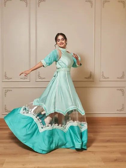 Introducing 'Jasmine', a beautiful indo-western gown in a refreshing teal color. The design features unique sleeves and a sheer panel on the skirt for a modern touch.