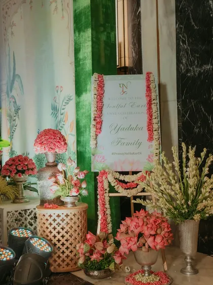 The welcome sign for the Myra ceremony, adorned with garlands of fresh flowers, reflecting the event's serene and traditional theme.