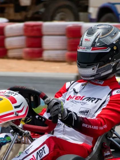 Professionalism is in the details. A close-up of our driver equipped with a BirelART racing suit and a BELL helmet, ready for the track. We partner with leading brands to ensure our drivers have the best and safest equipment.