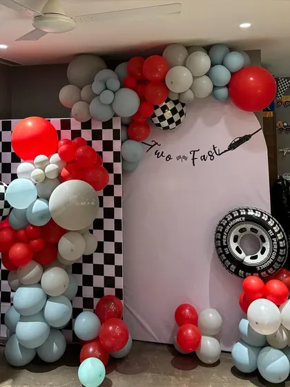 Ready, set, go! This "Two Fast" car-themed birthday is perfect for a second birthday celebration. The decor features a checkered flag backdrop, a balloon garland in red and blue, and a custom tire prop.