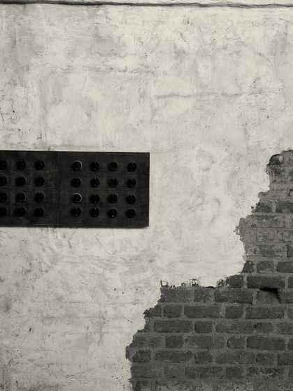 A detail of the wall treatment, where rough, exposed brick meets smooth, aged plaster. This textural contrast is a key element of the "lived-in" aesthetic.