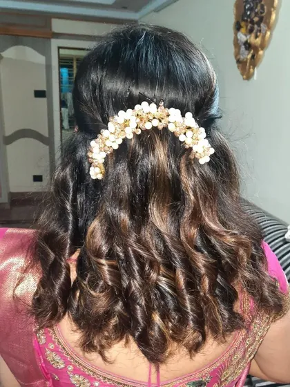 Soft curls on highlighted hair, styled with a pretty pearl and gold accessory.