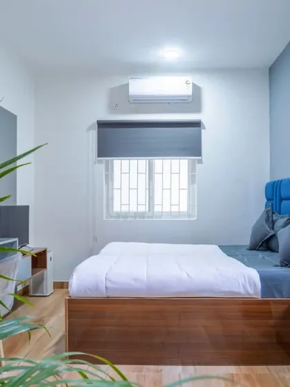 A completed bedroom in the Housr Nest co-living project in Koramangala. This real-world example highlights our focus on creating functional and comfortable living spaces, featuring a custom-built bed with a vibrant blue headboard, a compact study desk, and efficient use of space.