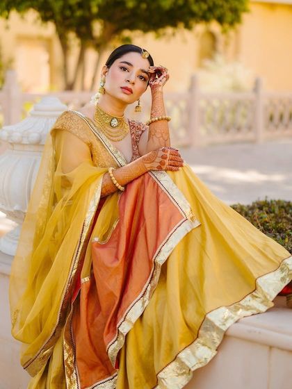 For her Haldi, Shree was inspired by Aishwarya Rai in Jodhaa Akbar. We created this regal look with a custom yellow and orange lehenga, paired with traditional gold jewellery.
