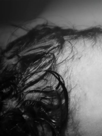 A close-up of the beautiful, wispy hair of a newborn right after birth. Black and white photography brings out the delicate textures of these first moments.