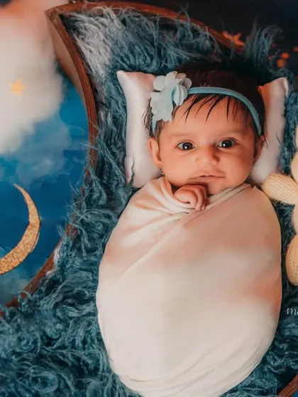 Awake and curious! This sweet 17-day-old newborn girl is taking in the magical moon and stars setup from her cozy crescent bed.