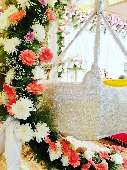 A silver cradle decorated with an abundance of fresh flowers for a naming ceremony.