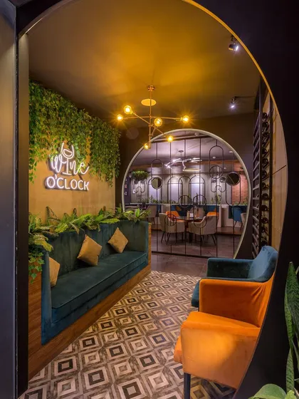 The circular motif is carried through from the arched entrance to the design of the space beyond. The combination of rich jewel tones, patterned floors, and greenery creates a luxurious and welcoming entryway.