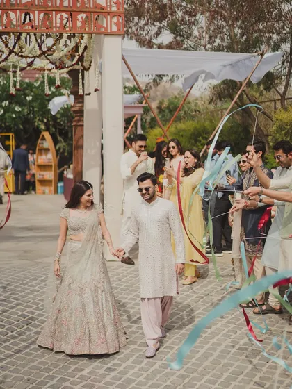 A joyful ribbon entry for the couple at their 'Artisan's Studio' Mehendi, with friends and family creating a colorful, welcoming pathway.