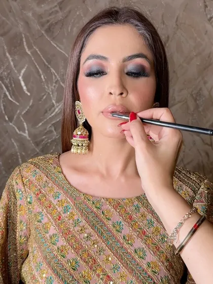 This is a classic Arabic makeup technique, focusing on a deep, bold, and black smokey eye. I'm applying the final touches to the lips, keeping them neutral to balance the intense eyes.