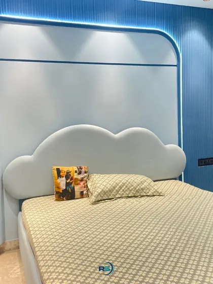 This whimsical bedroom features a custom cloud-shaped headboard and a soft blue and white color scheme. The curved wall panels with integrated backlighting add a dreamy and imaginative touch to the room.
