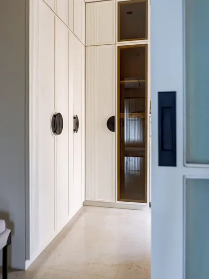 The walk-in wardrobe in the 'YBJ Residence' epitomizes minimalist elegance. Clean lines, neutral tones, and thoughtful organization create a realm of refined style and streamlined storage.