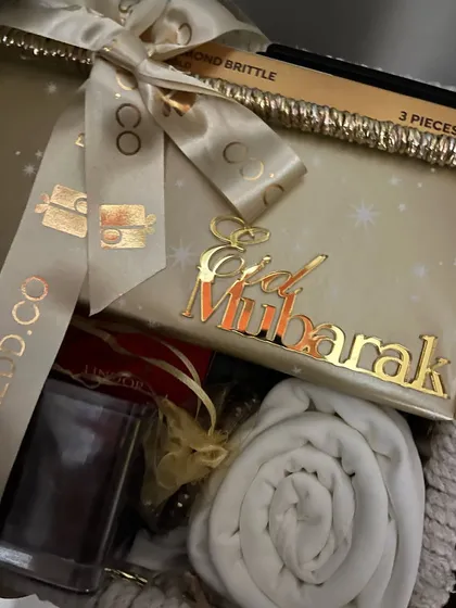 A close-up of an Eid hamper showing the golden "Eid Mubarak" acrylic tag and custom ribbon.