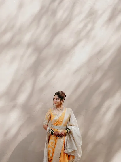 Draped in tradition, adorned with grace. This artistic shot captures the bride against a textured backdrop, letting her yellow Nauvari and my subtle makeup work shine.