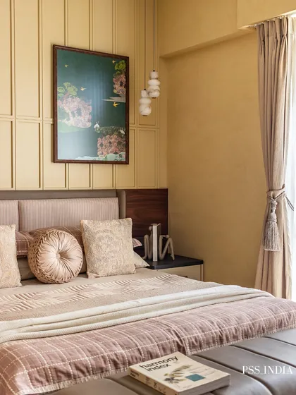 This bedroom is a sanctuary of warmth and texture. The paneled wall in a soft yellow hue, combined with dusty rose and beige bedding, creates a cozy and inviting atmosphere perfect for rest and relaxation.