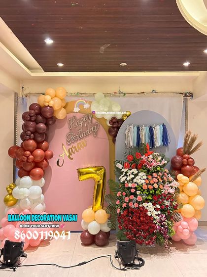 The same 7th birthday setup in natural light, showing the boho-inspired colors of the balloon arch and the tassel wall hanging.