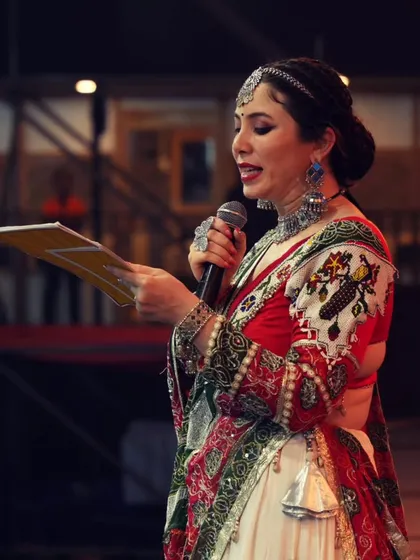 A side profile shot of me on stage during the Navratri festival, reading from my notes to ensure the event flows perfectly.