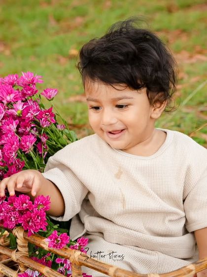 A sweet, gentle moment as the baby touches the pink flowers.
