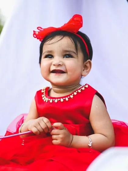 A beautiful, happy portrait of the birthday girl in her red dress. The close-up shot highlights her expression, with our clean and bright outdoor setup in the background.