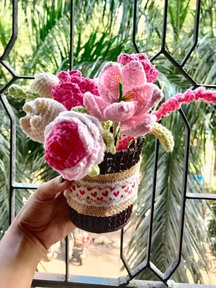 A beautiful basket filled with an assortment of pink and white crochet flowers. This arrangement includes roses, tulips, and lilies for a lush, full look.