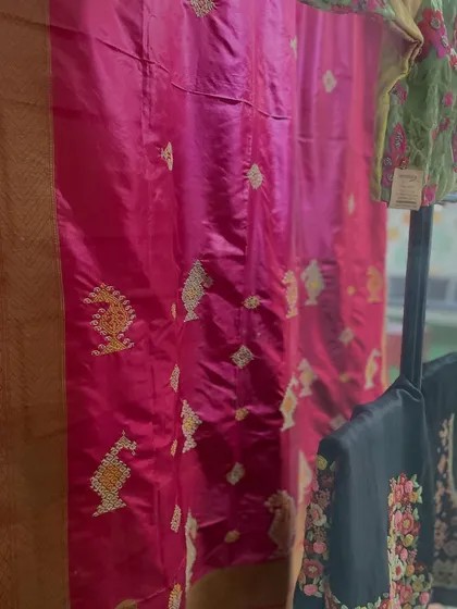 A glimpse of my studio, where finished sarees are ready for clients. You can see a rich pink Benarasi with Kasuti work and a black piece with colorful floral embroidery.