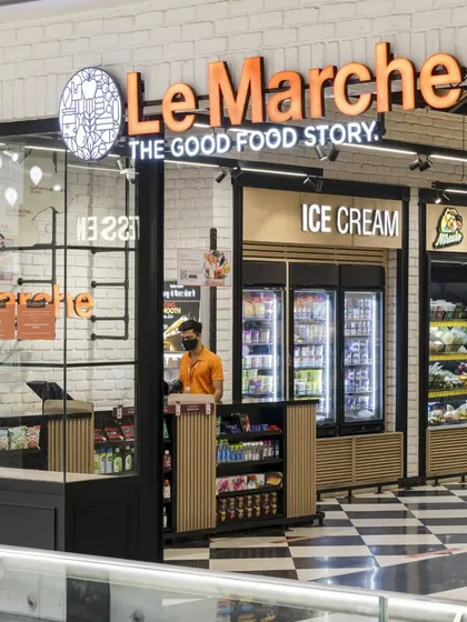 The checkout and entrance area of Le Marche features a dynamic design with a dedicated ice cream counter. The use of natural wood slats, white brick, and bold signage creates a welcoming and energetic first impression.